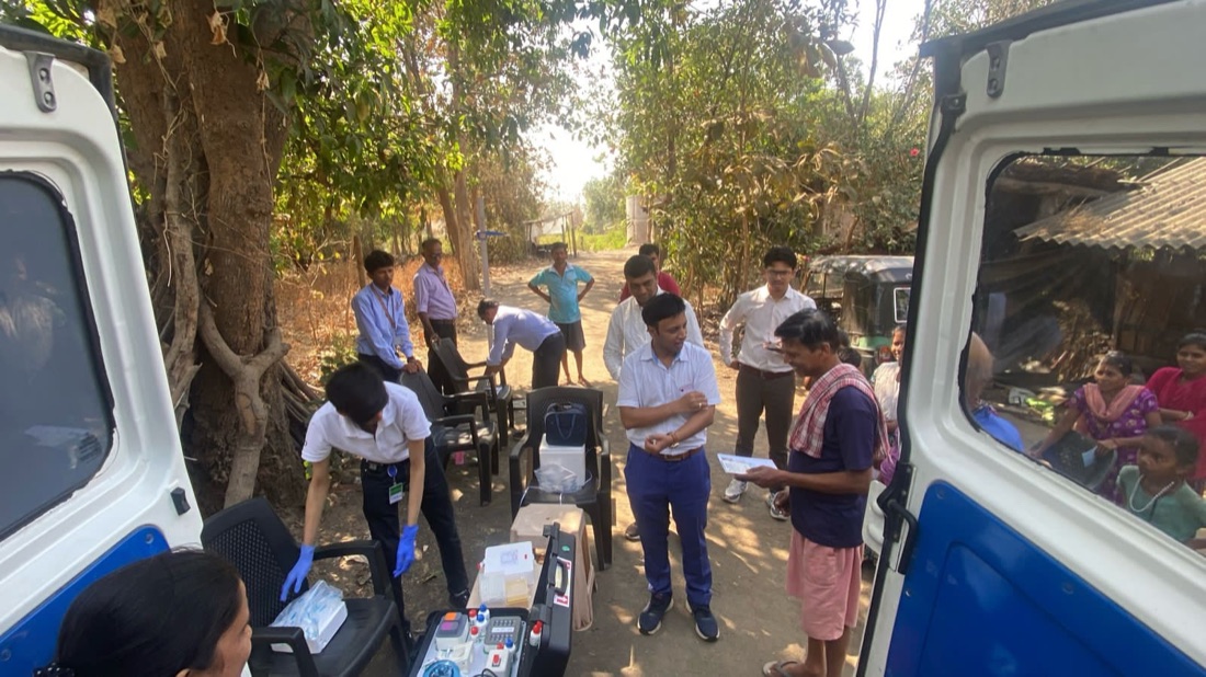 A mobilab community health camp in Gujarat, with staff running portable diagnostics from a vehicle.