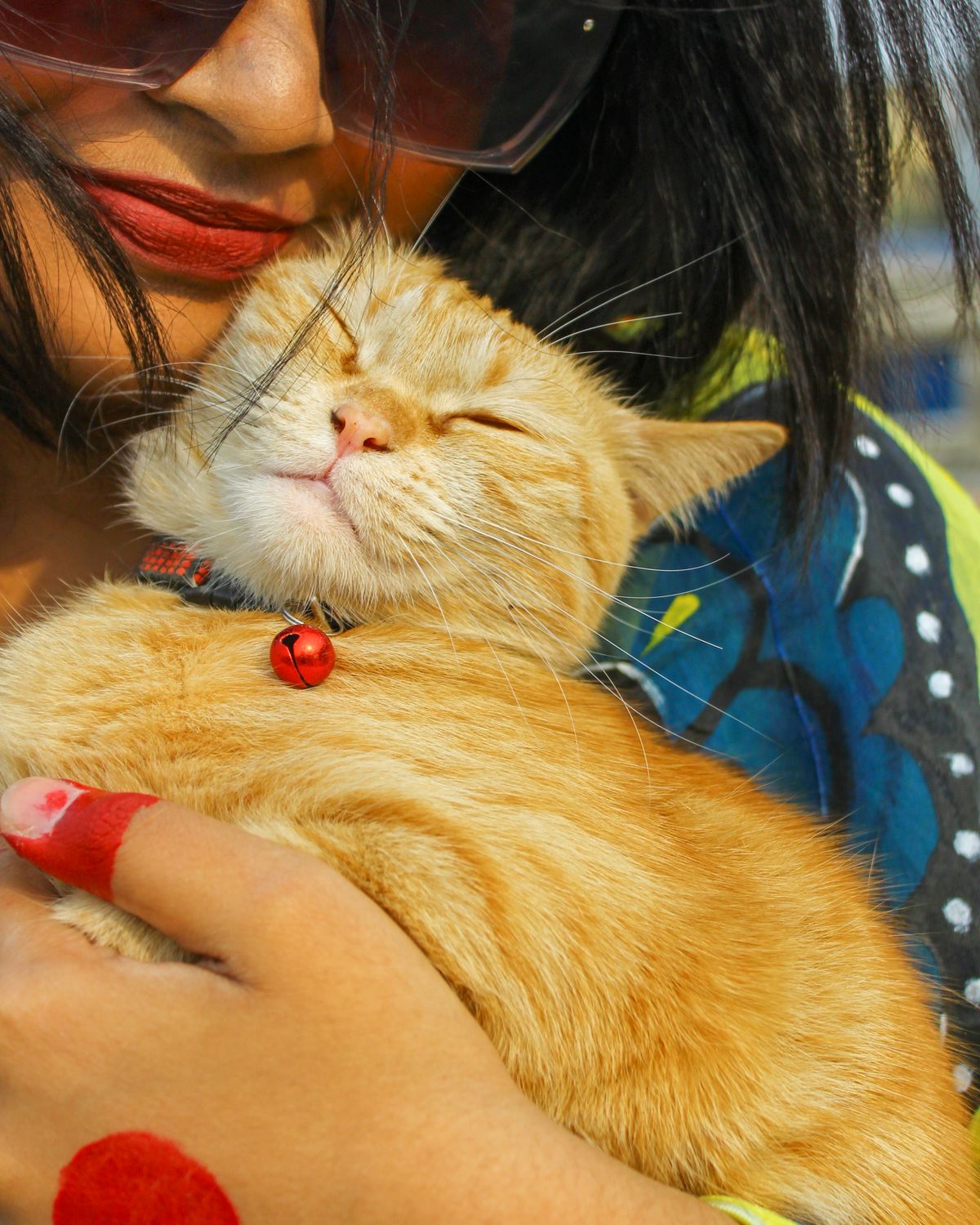A girl holding her ginger cat close.